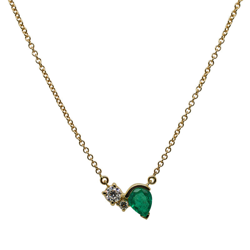 Front view of an asymmetrical round cut double diamond and pear cut emerald necklace in a 14 kt yellow gold setting with a gold chain.