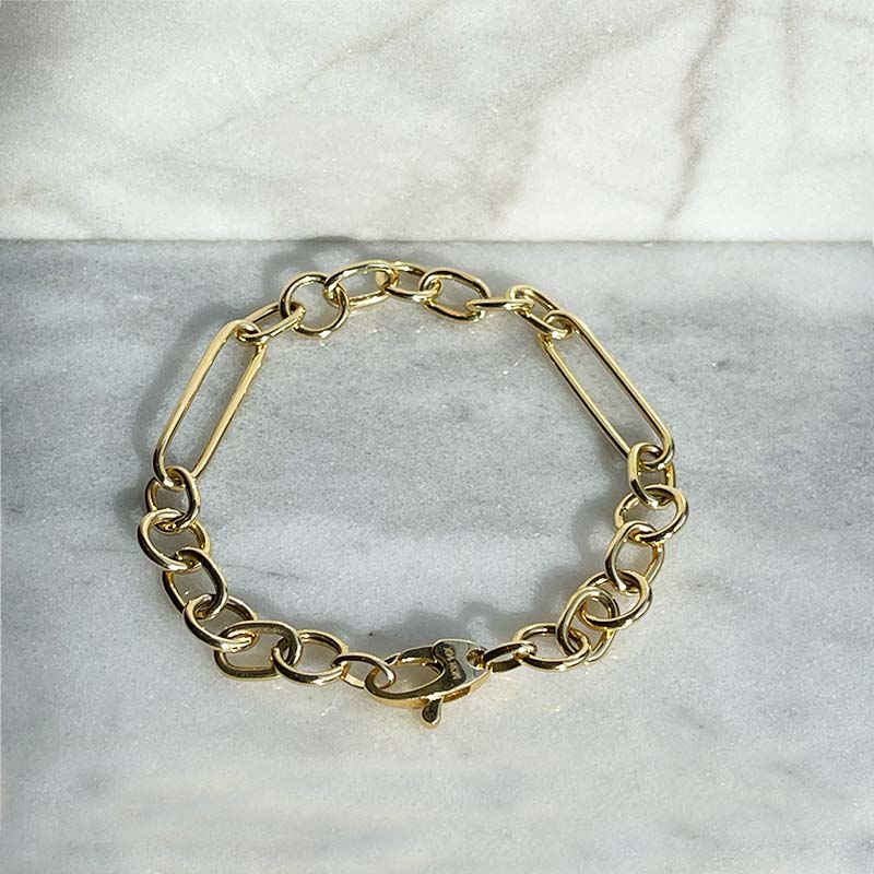 Overhead view of a solid 14kt yellow gold 7" bracelet with a mixture of circular and paperclip style links and a lobster clasp style closure. 
