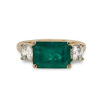 Front view of Columbian emerald ring flanked with 2 asscher cut diamonds set in 14 kt yellow gold.
