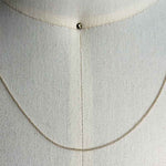 Close up of a dainty, solid 14 kt yellow gold rope style chain on a body form for scale.