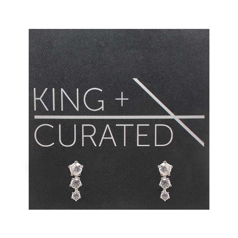 A pair of vertically stacked, triple crystal studs set in 925 sterling silver settings on King and Curated packaging.
