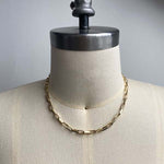 Front view on dress form of flat-link, squared edge paperclip necklace, cast in 14kt yellow gold.