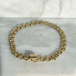 Overhead view of a solid 14kt yellow gold 7" vintage style multi ring/link bracelet with a box clasp style closure. 