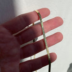 Image of 3mm 14k herringbone chain draped across finger in natural sunlight.