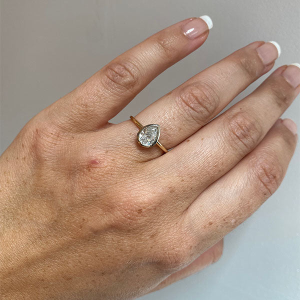 
                  
                    Load image into Gallery viewer, Front view on left ring finger of a bezel set, pear cut, salt and pepper diamond solitaire ring cast in 14 kt yellow gold by King + Curated.
                  
                