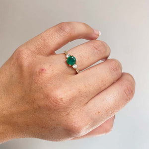 
                  
                    Load image into Gallery viewer, Front view on left ring finger of round emerald ring with 2 medium and 6 small accent diamonds cast in 14 kt yellow gold.
                  
                