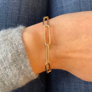 
                  
                    Load image into Gallery viewer, Front view on wrist of a paperclip style bracelet with a thinner gauge link cast in solid 14 kt yellow gold.
                  
                