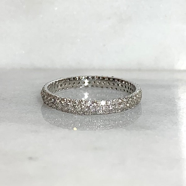 Front view of diamond pave eternity band in 14kt white gold on marble tile. Band is 3mm wide and Pave diamonds are offset have a total carat weight of 0.9.