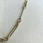 Close up image of larger paperclip chain with 3 round link in 14kt yellow gold.