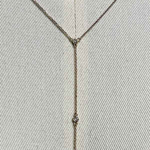 
                  
                    Load image into Gallery viewer, Close up of a lariat style necklace with 9 petite round cut, bezel set diamonds cast in 14 kt yellow gold settings on a body form for perspective.
                  
                
