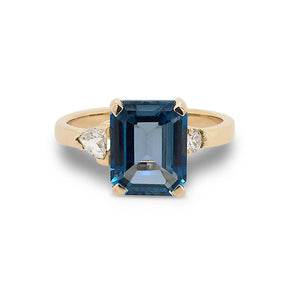 
                  
                    Load image into Gallery viewer, Front view of emerald cut London blue topaz and round and trillion cut diamond ring cast in 14 kt yellow gold.
                  
                