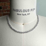 A necklace with round cut crystals set in a 925 sterling silver cluster setting on a body form for scale.