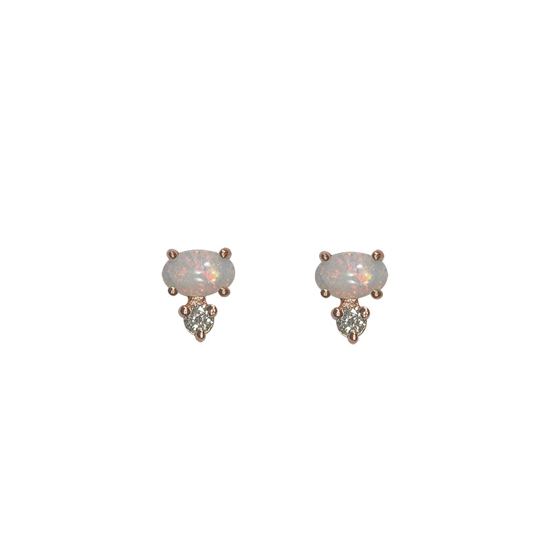 Front view of white oval opals, set east-west in 14 kt rose gold with 1 round accent diamond set vertically below each. Displayed on white background.