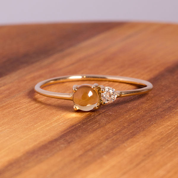 
                  
                    Load image into Gallery viewer, Front view on wood of cabochon cut citrine and round cut diamond ring cast in 14 kt yellow gold.
                  
                