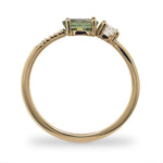 Side view of an asymmetrical oval cut, green sapphire and diamond ring cast in 14 kt yellow gold by King + Curated.