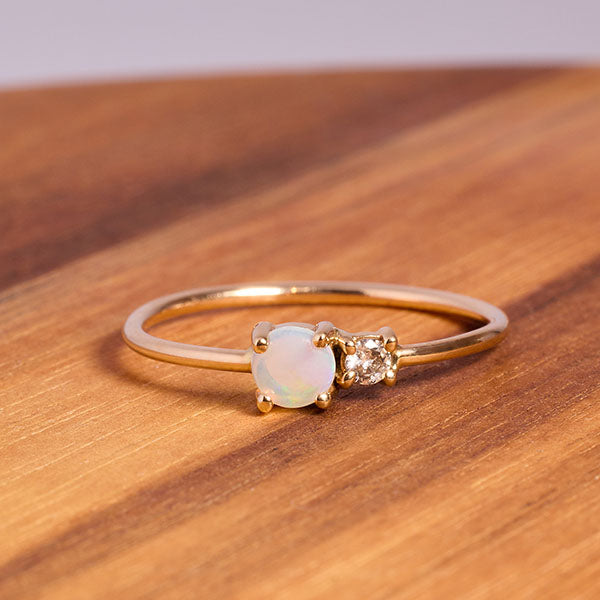 
                  
                    Load image into Gallery viewer, Front view on wood of petite moonstone and round diamond ring set in 14 kt yellow gold.
                  
                