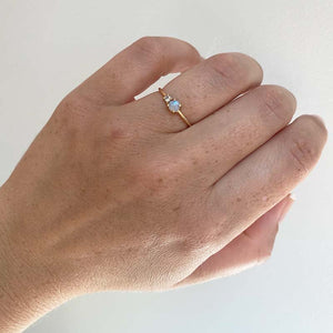 
                  
                    Load image into Gallery viewer, Front view on left ring finger of a cabochon opal and round diamond ring on a dainty band cast in 14 kt yellow gold.
                  
                