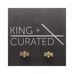 Pair of crystal studs with a champagne colored baguette with a smaller, white and round crystal on each side. Made of sterling silver with a 14kt yellow gold plating.