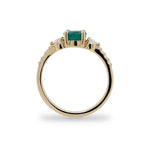 Side view of round emerald ring with 2 medium and 6 small accent diamonds cast in 14 kt yellow gold.