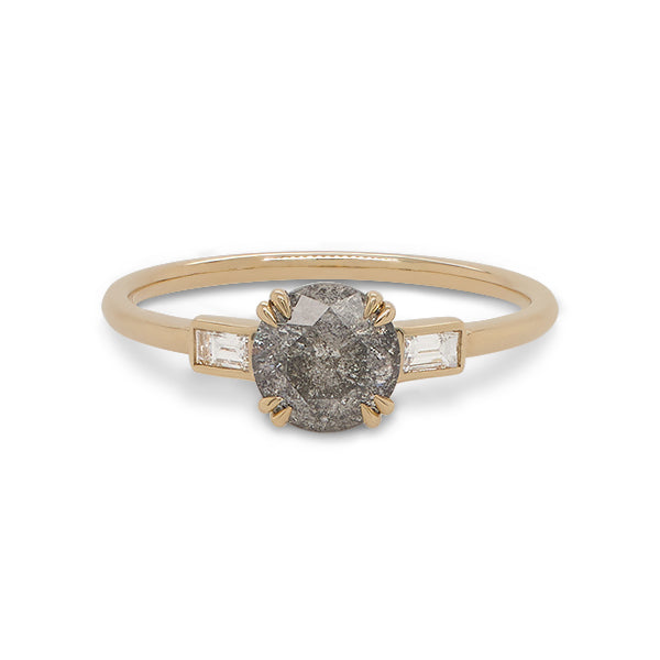 Front view of a round cut salt and pepper diamond ring flanked by 2 baguette cut diamonds, and cast in 14 kt yellow gold.