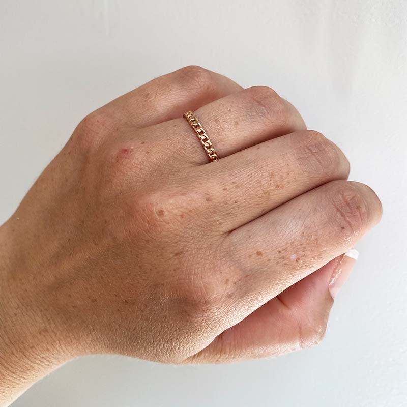 Front view on left ring finger of chain link pattern ring cast in 14 kt rose gold.