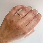 Front view on left ring finger of 14 kt yellow gold ring with repeat bead pattern.