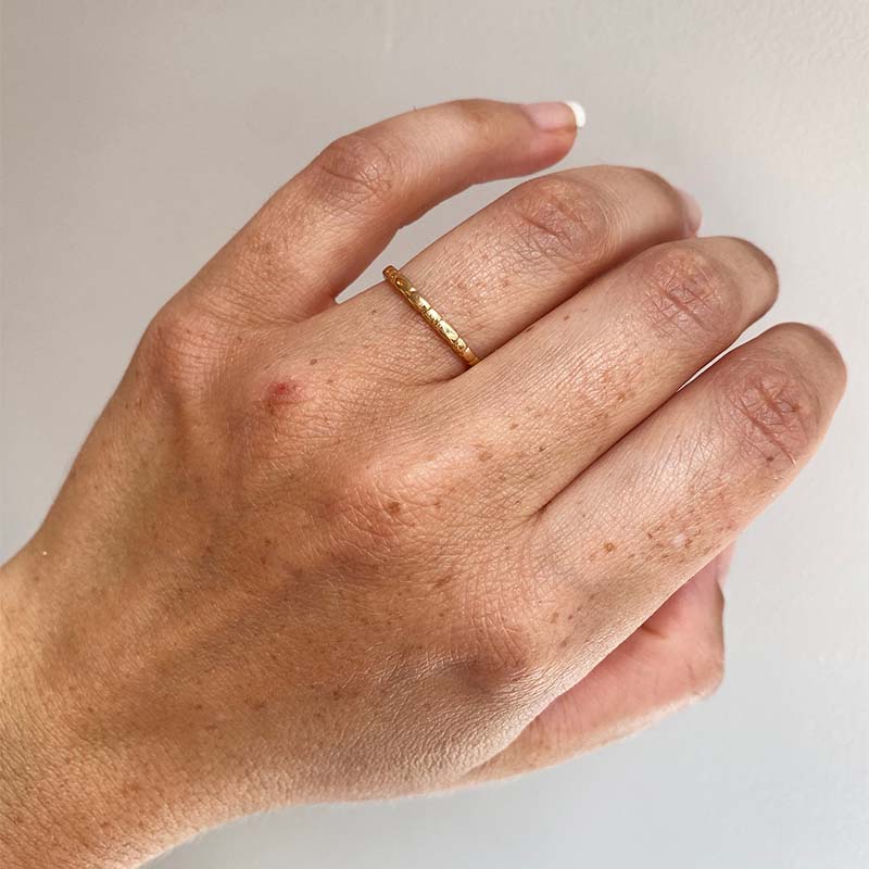 
                  
                    Load image into Gallery viewer, Front view on left ring finger of a stacking band with organic spaced lines casted in 14 kt yellow gold. 
                  
                
