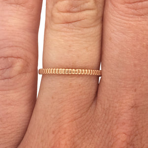 
                  
                    Load image into Gallery viewer, Ring with a lined pattern cast in 14 kt yellow gold on left ring finger.
                  
                