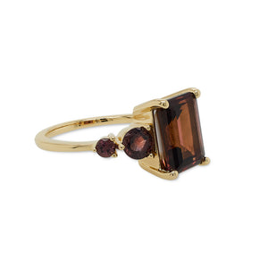 
                  
                    Load image into Gallery viewer, Left side view of an asymmetrical, emerald cut deep red tourmaline ring with a half moon cut and round cut pink sapphires and diamonds cast in 14 kt yellow gold.
                  
                