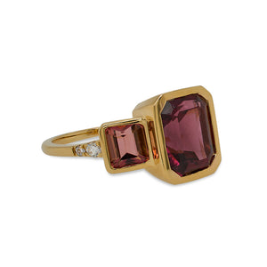 
                  
                    Load image into Gallery viewer, This left side view of a ring is cast in 18 kt yellow gold has a large 3.5 carat emerald cut rhodolite garnet in the center and is flanked by almost 2 carats of peach colored emerald and trillion cut tourmalines and tiny round cut diamonds.
                  
                