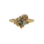 Front view of an east/west set light blue/green, shield cut sapphire ring flanked by a half moon and baguette cut diamond, and cast in 18 kt yellow gold.