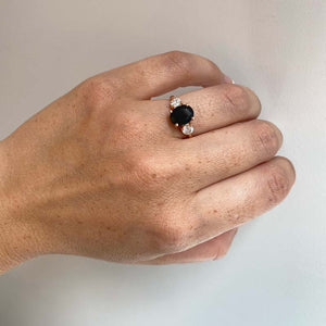 
                  
                    Load image into Gallery viewer, Front view on left ring finger of oval cut black sapphire and round cut diamond ring set in 14 kt rose gold.
                  
                