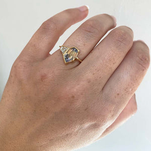 
                  
                    Load image into Gallery viewer, Front view on left ring finger of a light blue with yellow bicolor sapphire, cut in an irregular geometric shape with a trapezoid cut white diamond set alongside. Cast in 18 kt yellow gold.
                  
                