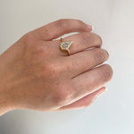 Front view on left ring finger of a 1.32 ct, kite cut diamond solitaire ring cast in 18 kt yellow gold.