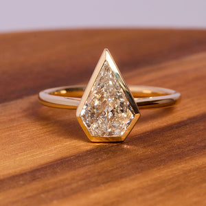 
                  
                    Load image into Gallery viewer, Front view on wood of a 1.32 ct, kite cut diamond solitaire ring cast in 18 kt yellow gold.  
                  
                