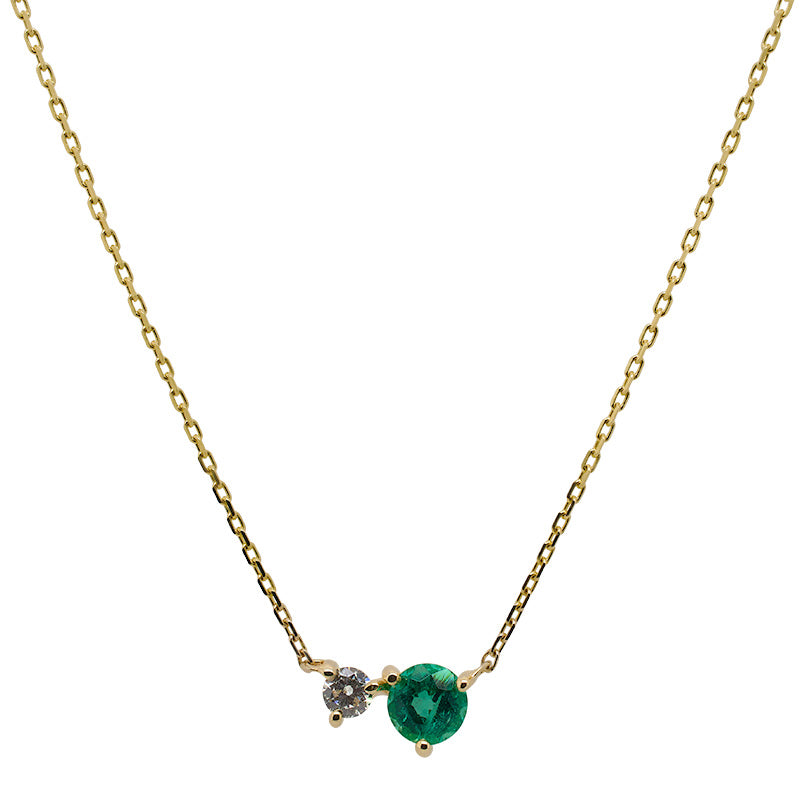 Front view of an asymmetrical round cut emerald and diamond necklace cast in 14 kt yellow gold.