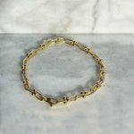 Overhead view of a solid 14kt yellow gold U link and pinball style 7" bracelet with a lobster clasp style closure. 