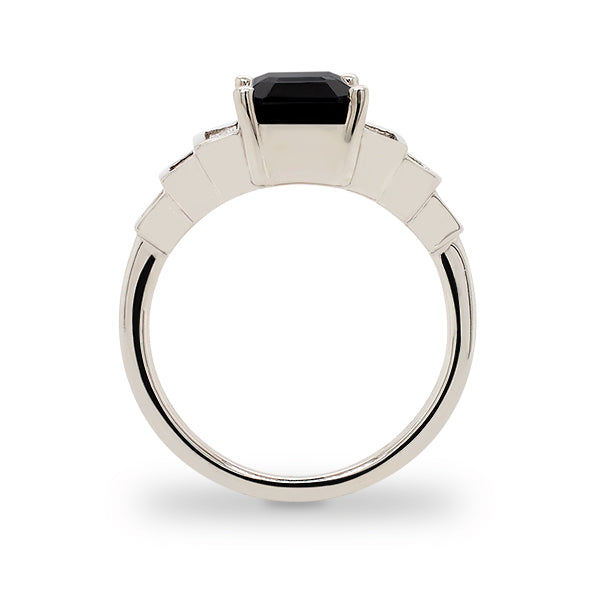 Side view of emerald cut black sapphire ring with 6 baguette cut diamonds set in 14 kt white gold.