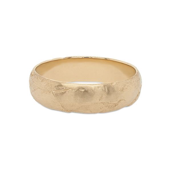 Front view of a 6.5 mm wide rounded band with an organic texture cast in 14 kt yellow gold.