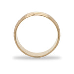 SIde view of a 6.5 mm wide rounded band with an organic texture cast in 14 kt yellow gold.