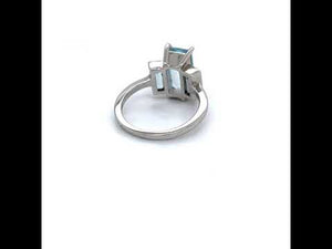 
                  
                    Load and play video in Gallery viewer, 360 video of a three stone aquamarine ring with one larger, emerald cut center stone flanked by two baguette cut stones set in a 14 kt white gold setting.
                  
                
