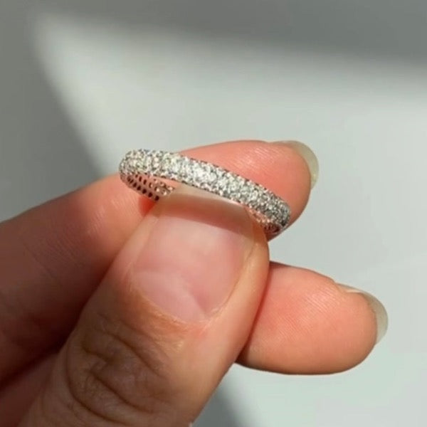 
                  
                    Load image into Gallery viewer, View of diamond pave eternity band in 14kt white gold held up to lens in natural sunlight. Band is 3mm wide and Pave diamonds are offset have a total carat weight of 0.9.
                  
                