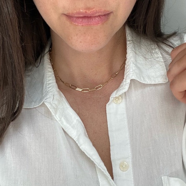 View of extra fine paperclip in 14kt yellow gold being worn along collar with a white button down shirt.